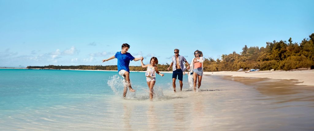 Familia disfrutando de la playa durante unas vacaciones en crucero con ropa de baño.