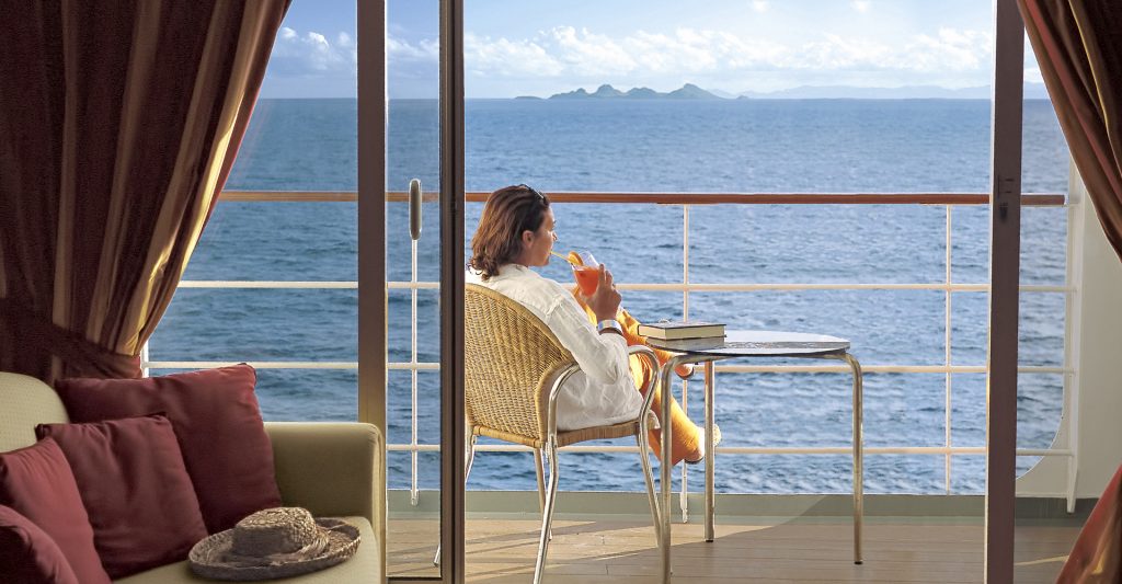 Mujer en el balcón de su camarote MSC Cruises en su crucero cultural por el Mediterráneo Mujer relajándose y tomando un cocktail en el balcón de su camarote MSC Cruises en su crucero cultural por el Mediterráneo