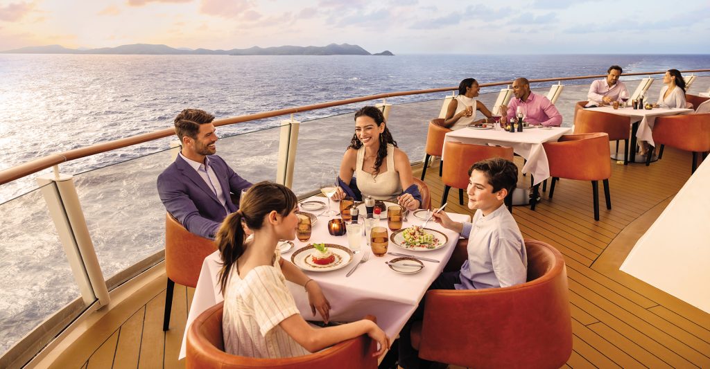 Crucero en Familia: Unos padres disfrutan con sus hijos de una cena a bordo del NCL Encore Imagen de unos padres disfrutando con sus hijos de una cena a bordo del NCL Encore en su crucero en familiar