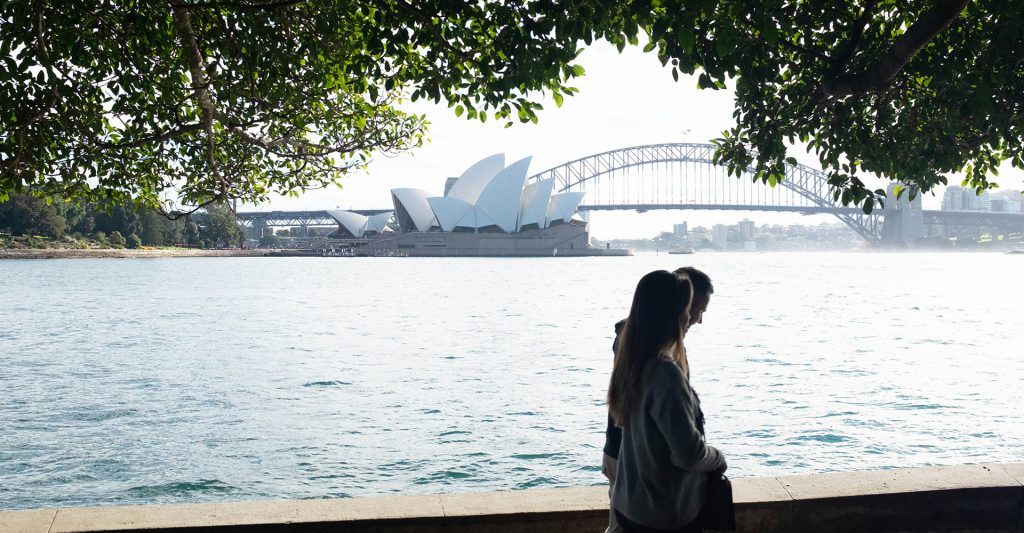 Pareja paseando con la Ópera de Sídney de fondo Imagen de una pareja paseando mientras observan la Ópera de Sídney de fondo