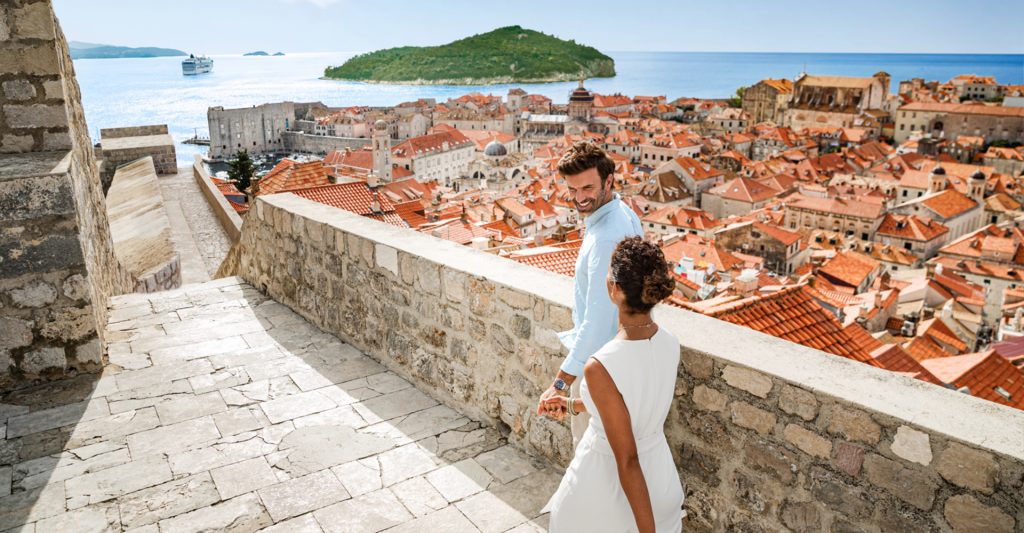 Imagen de una pareja paseando en la ciudad de Dubrovnik con el Norwegian Pearl de fondo