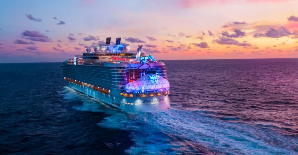 Crucero iluminado navegando en el mar al atardecer con decoración festiva