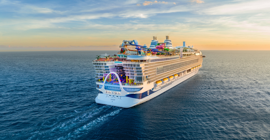 Crucero navegando al atardecer con el mar en calma y cielo dorado.