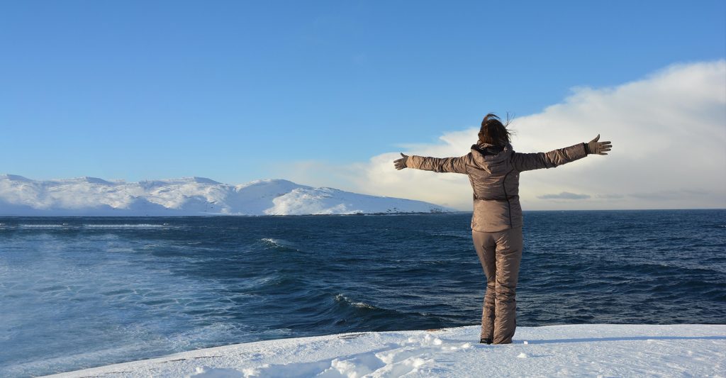 Fotografía de una mujer en la nieve en Islandia, destino de crucero
