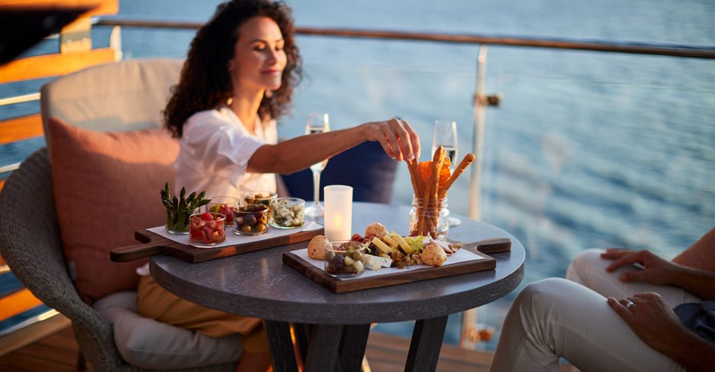 Crucero Todo Incluido: Imagen de una mujer tomando un aperitivo, mirando las vistas al mar, a bordo de un crucero Celebrity