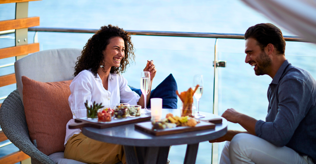 Fotografía de una pareja sentados riéndose en un crucero por europa
