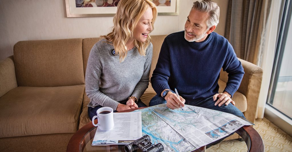 Imagen de una pareja planificando su escala de crucero en el camarote de Princess Cruises con un mapa 