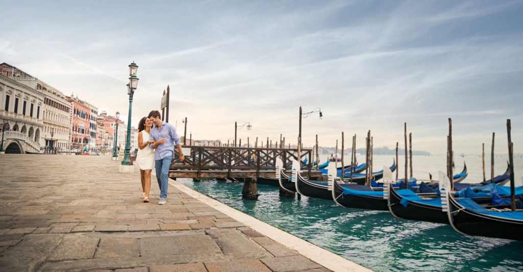 Pasear junto a la laguna veneciana, uno de los grandes placeres de un crucero por Venecia Pareja paseando junto a las góndolas en la laguna de Venecia durante una escala de crucero