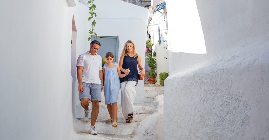 Descubriendo los pueblos tradicionales de las Islas Griegas en crucero Familia paseando por las calles blancas de una isla griega durante una escala de crucero