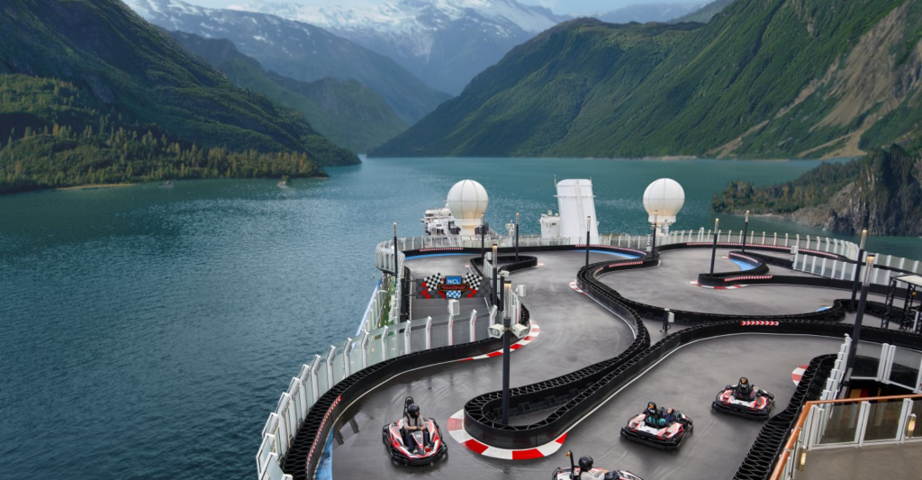 Entretenimiento a bordo del Norwegian Prima de Norwegian Cruise Line. Pista de carreras de karts en la cubierta superior del barco Norwegian Prima navegando entre montañas.