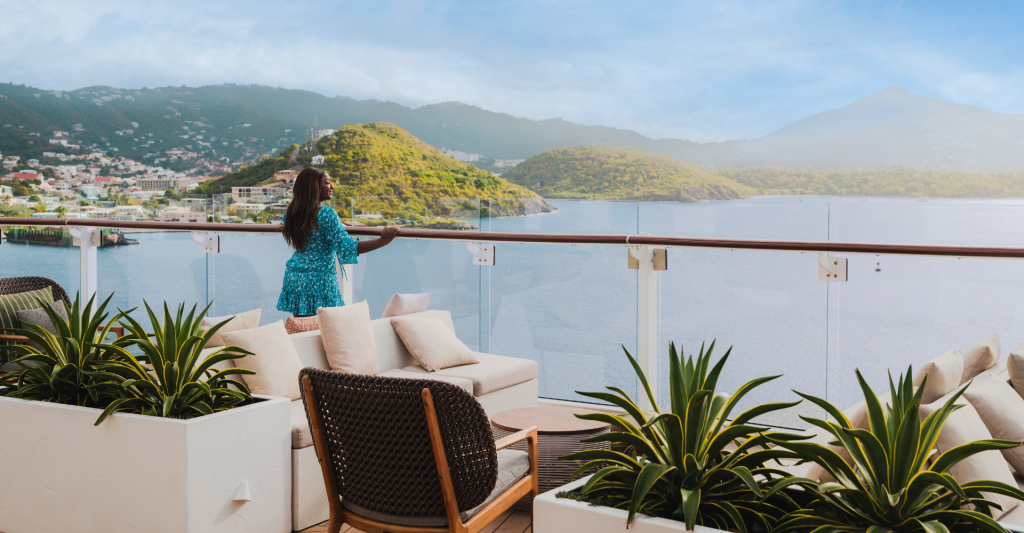 Vistas al Caribe desde la cubierta de un crucero para una Luna de Miel Mujer contemplando una isla del Caribe desde la cubierta de un crucero durante su Luna de Miel