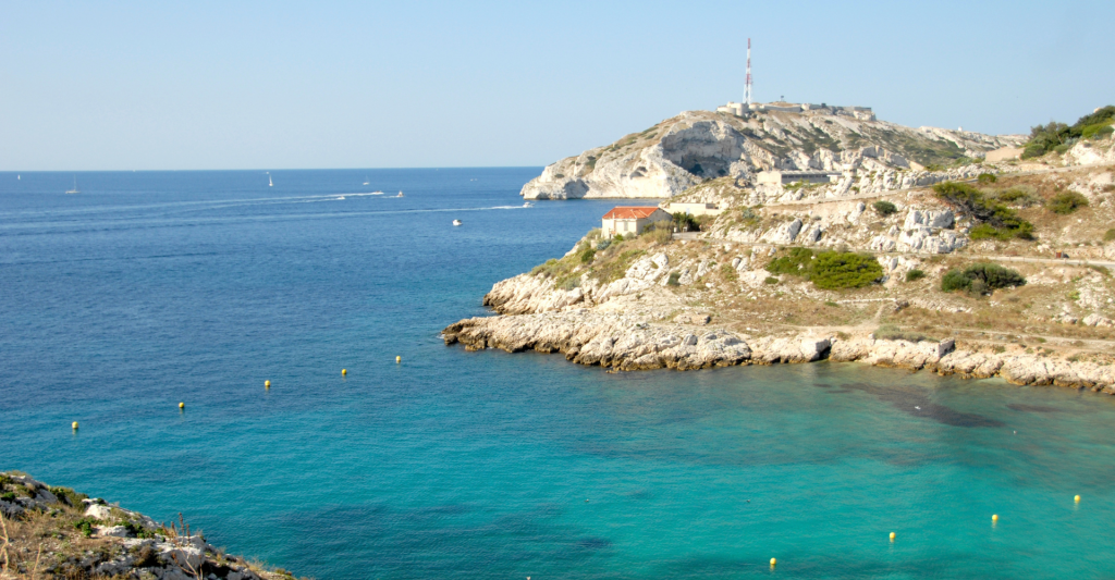 Cala rocosa de aguas cristalinas en el Mediterráneo Paisaje costero de una cala de aguas turquesas rodeada de acantilados rocosos y colinas bajo un cielo despejado