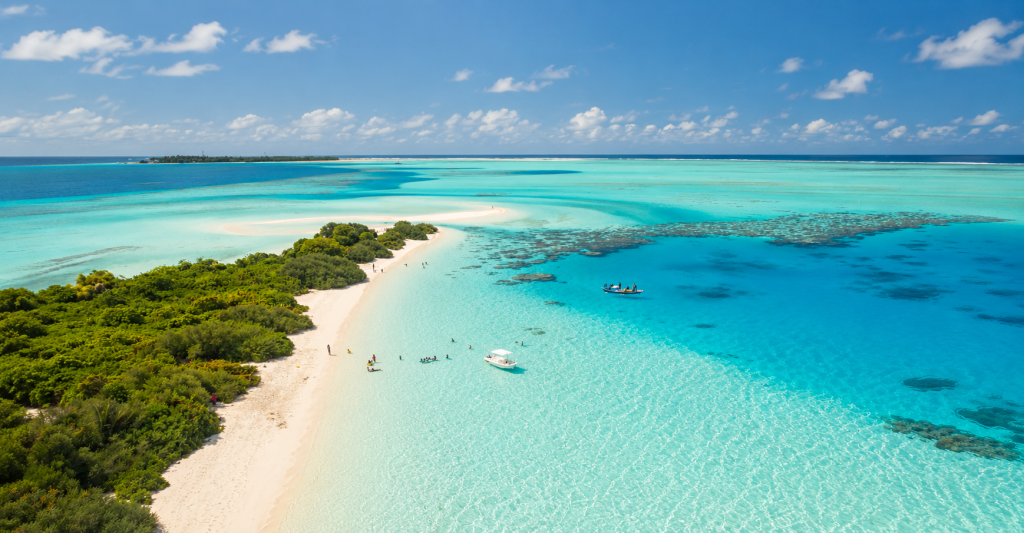 Vista aérea de una isla caribeña rodeada de aguas turquesas y arrecifes

